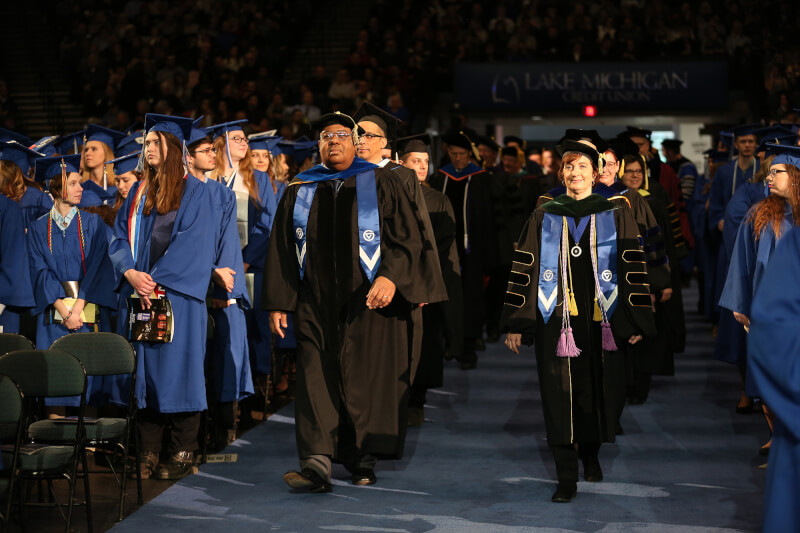 group of people in academic regalia walking down aisle