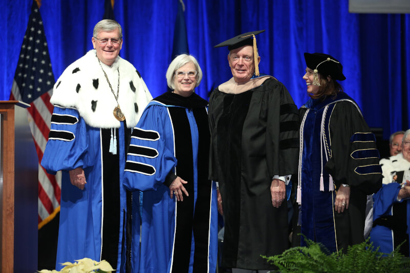 four people standing in academic regalia
