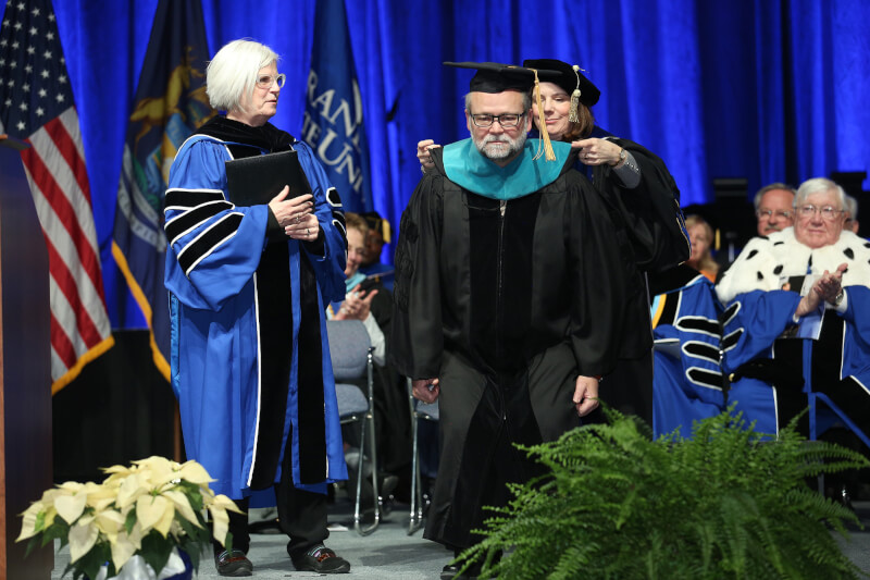 women presenting academic stole to man