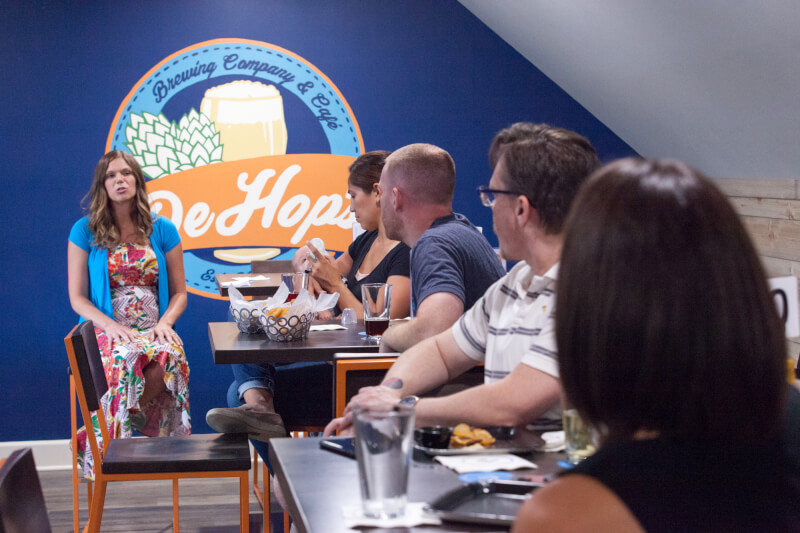 woman seated talking in a restaurant to groups at tables