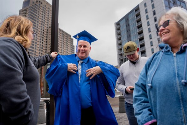 A graduate fixes their cap and gown prior to Commencement.
