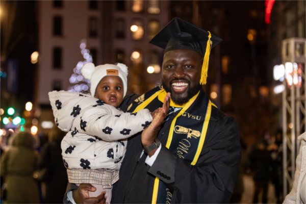 A graduate high fives a baby during Commencement.