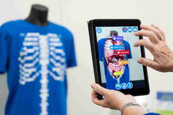 A person uses a touch screen device showing human anatomy.  