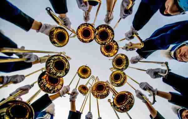 Marching band trombone players hold their instruments over their heads during a hype cheer.  