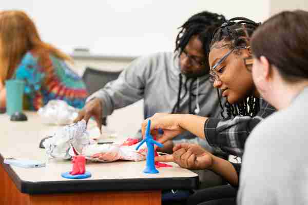  College students work together on a project in a classroom setting. 