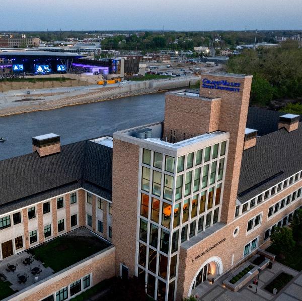 Aerial photo of L. William Seidman Center with Grand River and Acrisure Amphitheater in the background at dusk.