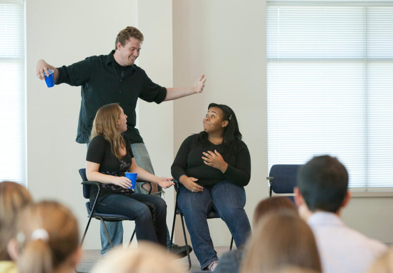 Photo of React troupe performing for students.