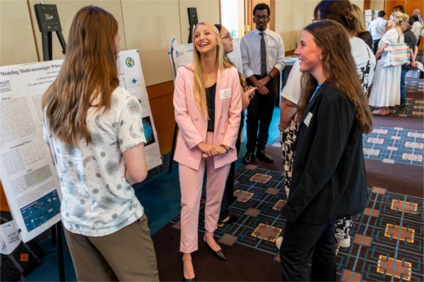 A student discusses her research with peers during the Summer Scholars Showcase.
