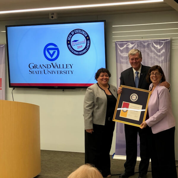 one man and two women standing with large framed certificate