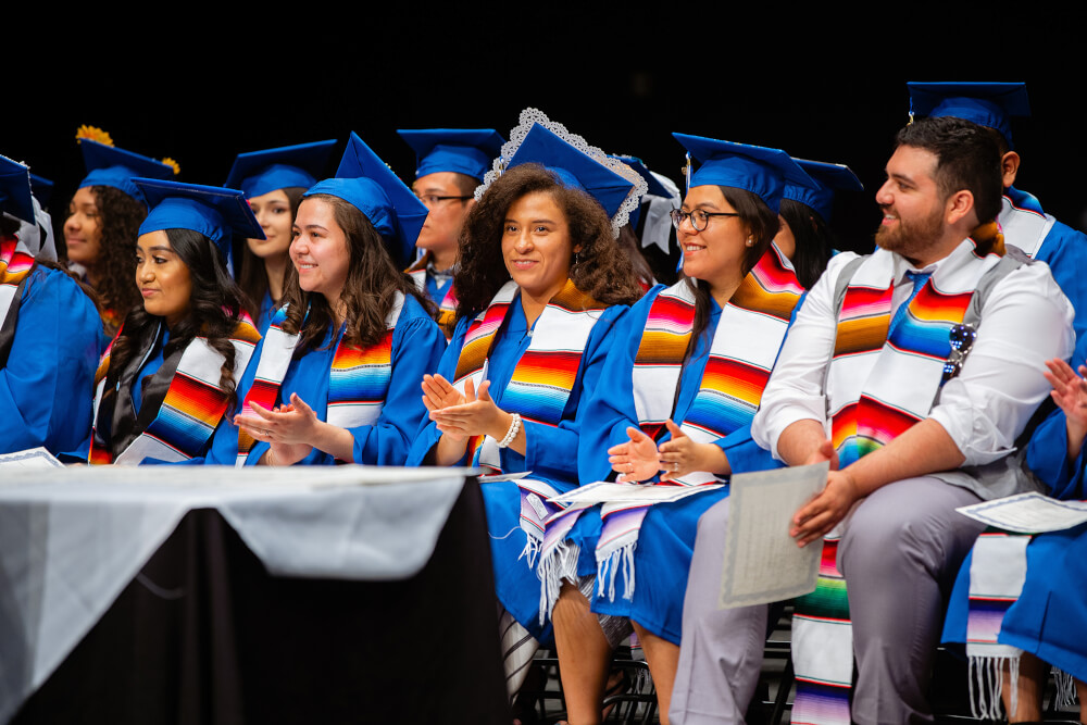 row of students in caps and gowns with Latino stolls