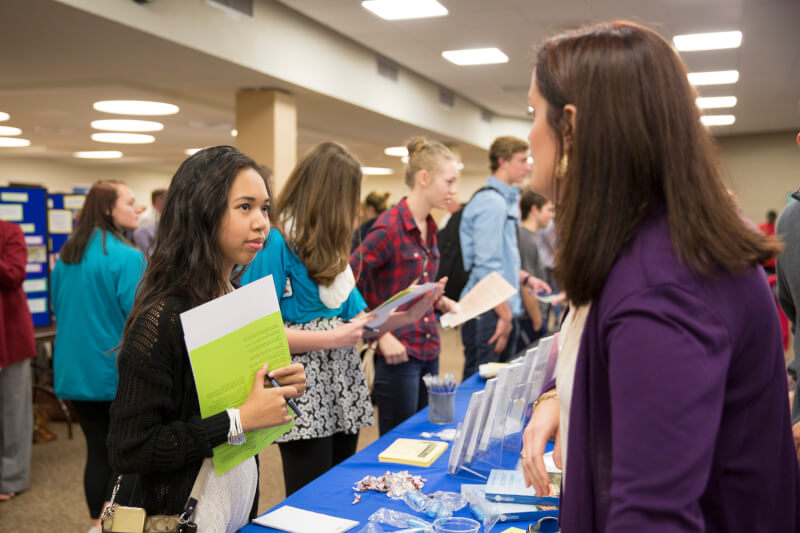 A photo of a student at a fair on campus.