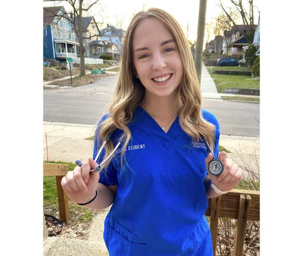 Natalie VeCasey is pictured in a blue KCON shirt and holding a stethoscope
