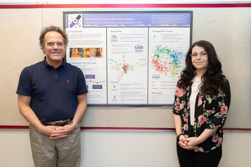 two people standing in front of research poster