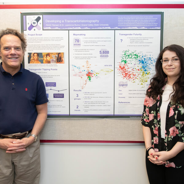 two people standing in front of research poster