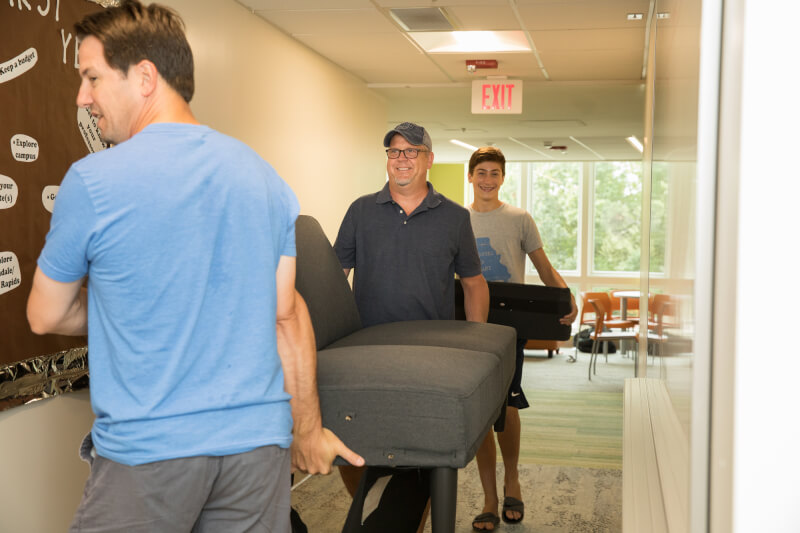 Students and families carry personal possessions down a hallway during move-in 2017.