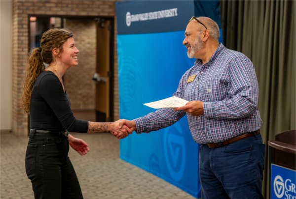 Tim Marroqu&#237;n gives a certificate to Abigail Austin during the Alpha Sigma Lambda Honor Society induction ceremony as part of the Sigma Lambda Sigma Chapter of GVSU