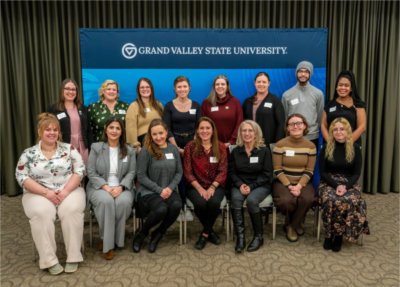 two rows of students, one seated one standing, in front of GVSU horizontal banner