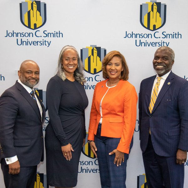 four people standing in front of John C. Smith University backdrop