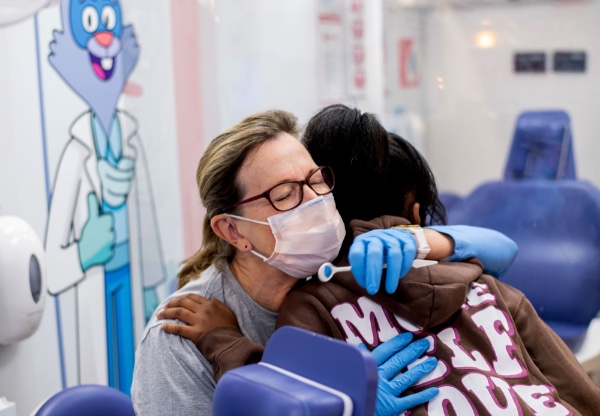 A dental hygienist receives a hug from a girl after a dental screening.