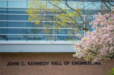 flowering trees in spring in front of Kennedy Hall of Engineering building and signage