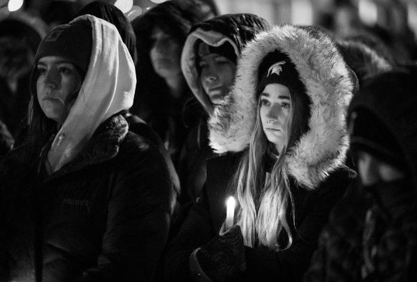 A student wearing an MSU hat stands in the crowd at the vigil.