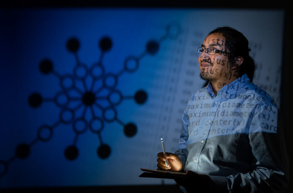 man standing with iPad, reflection of math formulas on his face