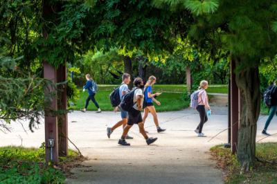 people walking on campus, green trees and green grass 