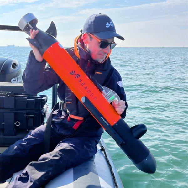 A researcher prepares to drop an autonomous underwater vehicle into the water. 