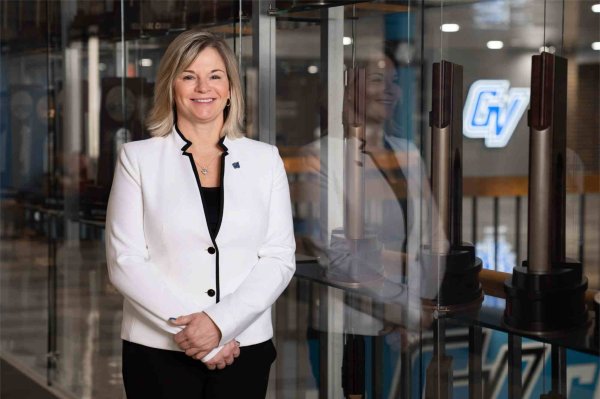 GVSU Director of Athletics Keri Becker poses for a portrait in the Fieldhouse Arena amid many of the trophies GVSU teams have won.
