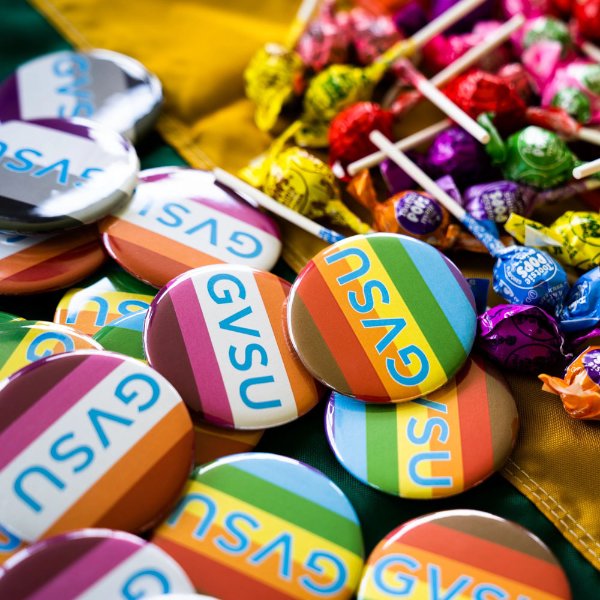 Buttons with various pride flags sit in a pile. They all read GVSU.