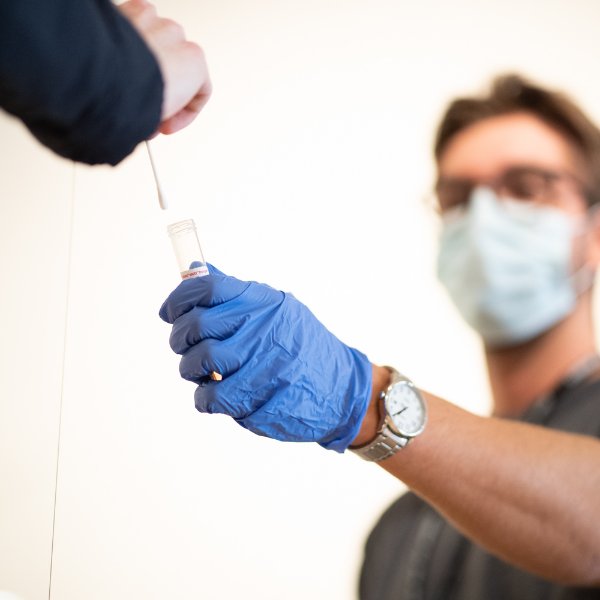 Nose swab being inserted into a test tube.