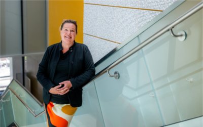 Melanie Shell-Weiss stands in the well-lit stairwell of the Mary Idema Pew Library. 