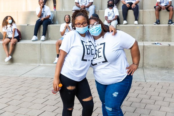 Two peer mentors stand next to each other at Black Excellence Orientation, they are wearing masks.