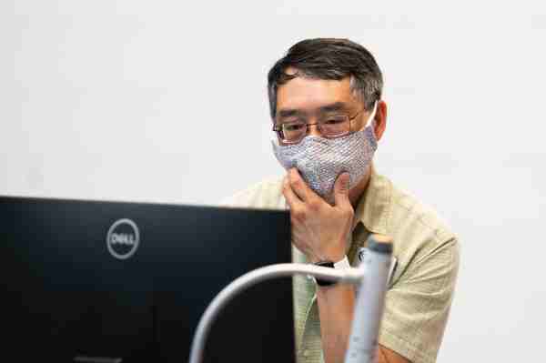 Kin Ma at computer, wearing a mask