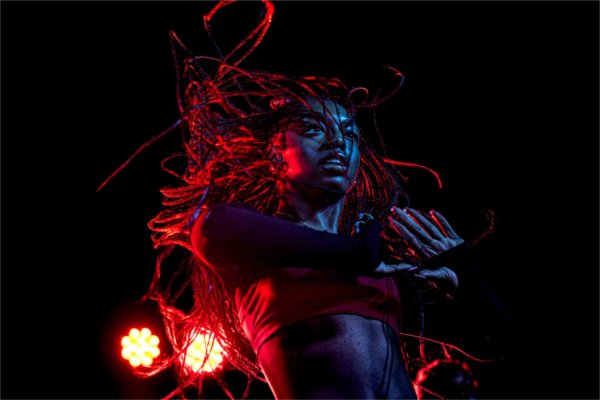  Red and light lights highlight a dance as their braids flow in the air. 