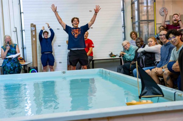  College students raise their hands in celebration during a small regatta boat race. 