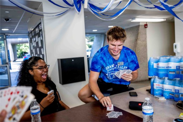  Two students laugh as they play cards together in a housing unit on a college campus. 