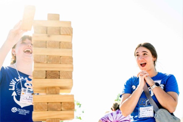  Two college students react with smiles and surprise while playing Jenga -- a wooden game. 