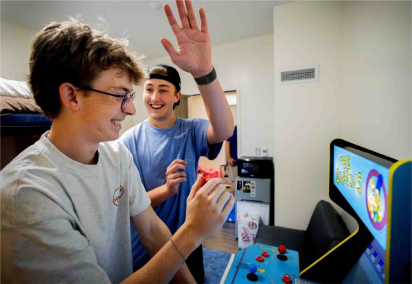  Two college students high five while playing an arcade game. 