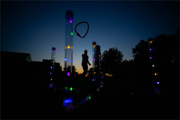  A student is silhouetted as they play a light-up ring toss game. 
