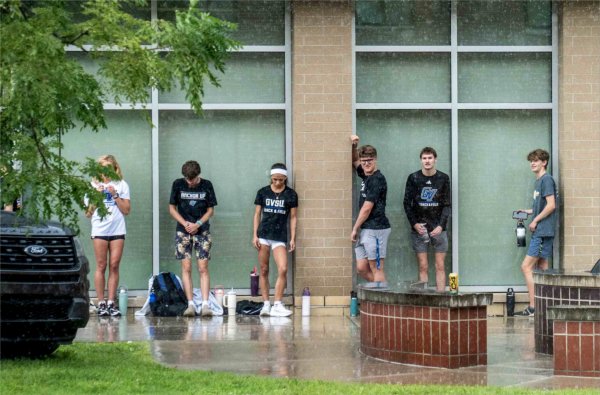  Track and field college students hide under the eaves to stay out of the rain. 