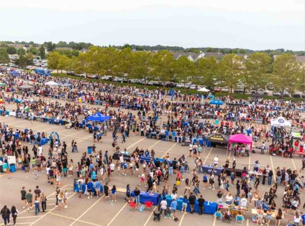  A large parking lot is full of students and tables during an event on a college campus. 
