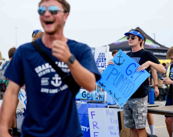  Holding a blue sign, college students encourage people to come to their table. 
