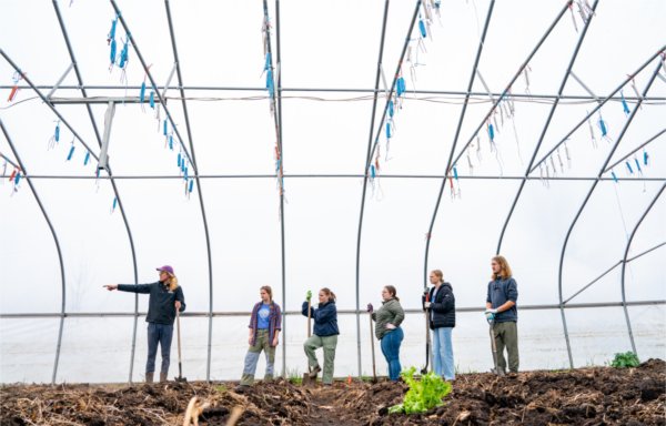  Students with shovels stand in a greenhouse ready to work. 