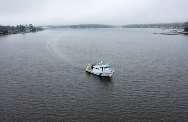  A research boat makes its way through the water as seen from a drone on a foggy day. 