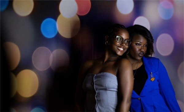  Two college students pose for a photo in front of a colorful photo backdrop. 