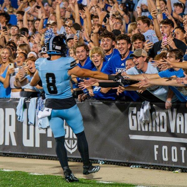 GVSU students celebrate a touchdown with a GVSU football player. 