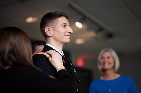 Lt. Jackson Wierenga has officer rank insignia pinned on him by his wife as his mother looks on.
