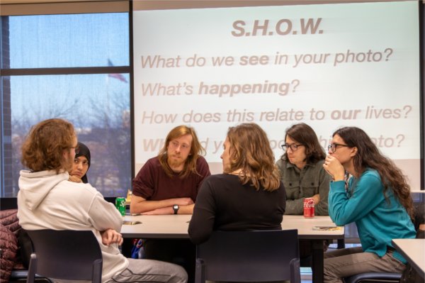 four students at table with projection in background, SHOW, what do we see in your photo? and other questions