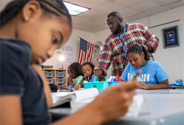 Charles Ball stands behind third graders (from left) Averi Clark, Annicia Roddie, Karter Mitchel and Raelynn Smith, who are at desks, with multiplication at Challenger Elementary in Kentwood.